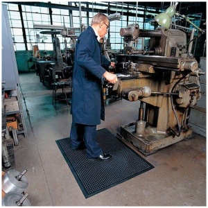 A man standing in front of a factory floor mat.