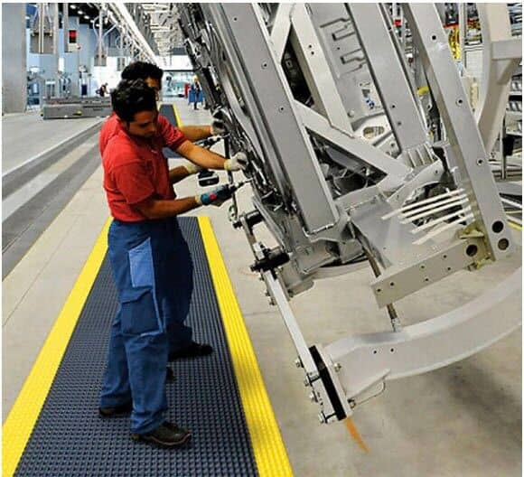 Two fatigued men working on a machine in a factory.