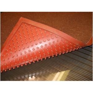 A red rubber Grip Rock Floor Mat with grip holes on a rock floor.