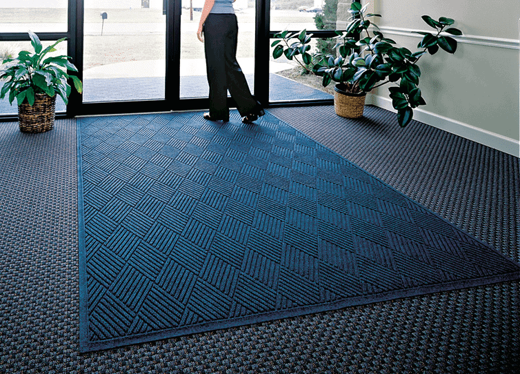 A woman posing with a WaterHog Fashion Diamond Floor Mat.