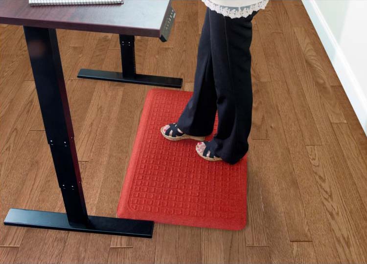 A woman using the Get Fit Stand Up Anti-Fatigue Floor Mat while standing.