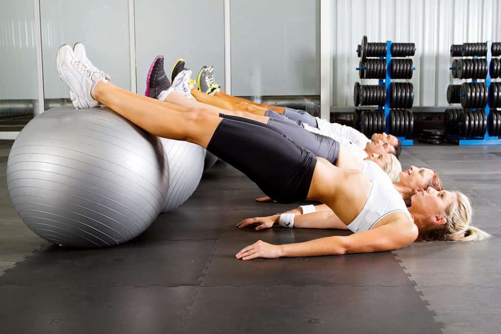 A group of women doing sit ups on exercise balls.