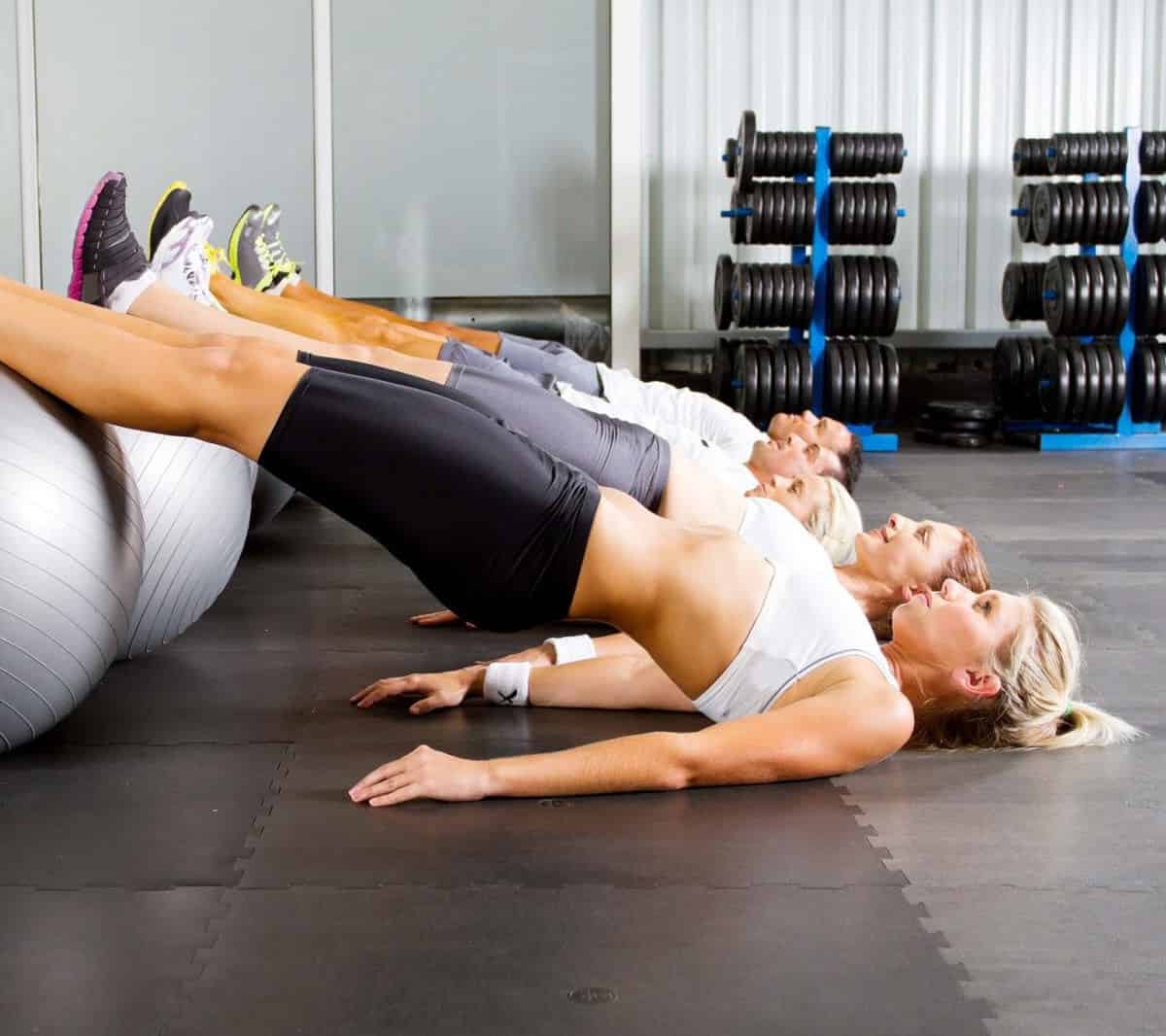 A group of women doing sit ups on exercise balls.