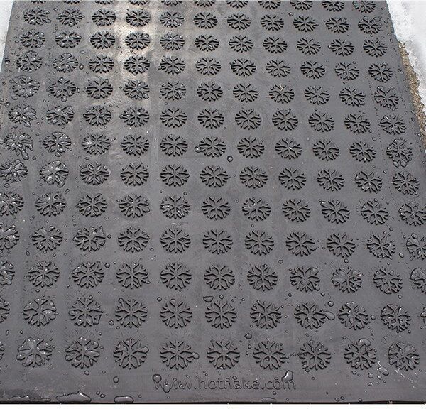 A black HOTFlake Walkway / Driveway Mat with a pattern of flowers on it.