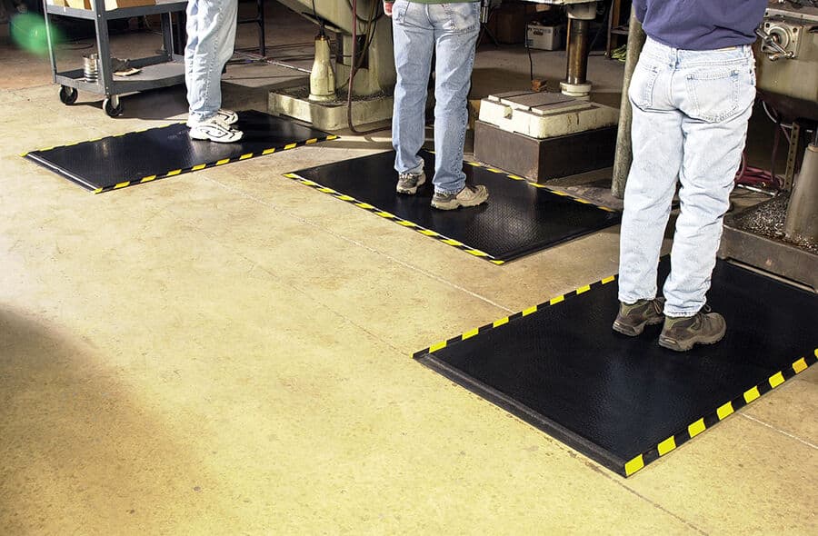 A group of people standing in front of a DuraComfort Grip Floor Mat for promotional purposes.