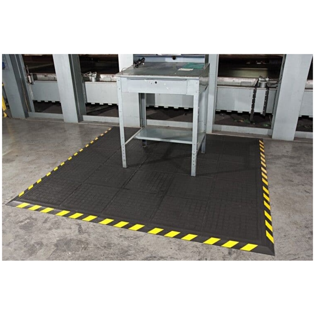 A black and yellow floor mat in a factory.