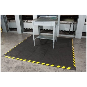 A black and yellow floor mat in a factory.