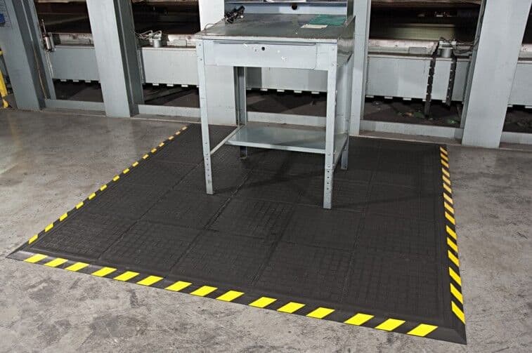 A black and yellow floor mat in a factory.