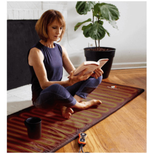 A woman sitting on the ToastiMat Heated Yoga Floor Mat.
