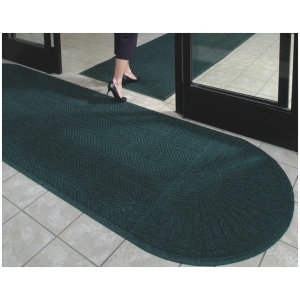 A woman standing in front of a door with a green mat.