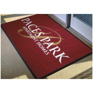 A red door mat with the words paces park apartment homes on it.