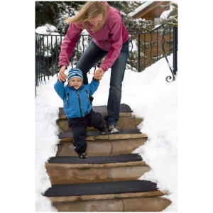 A woman is holding a child up on snowy HOT-blocks™ Stair Tread.