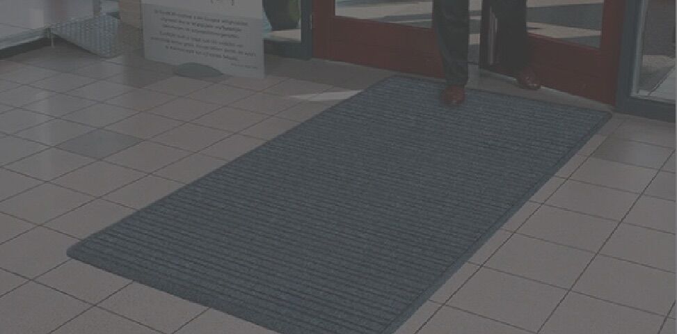 A man is standing in front of a door mat.