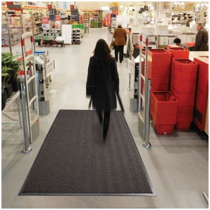 A woman shopping while stepping on an Arrow Trax™ Antimicrobial Floor Mat.