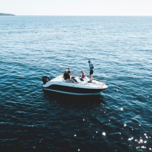 Two people engaging in water sports on a small motor boat, with slipping risks.