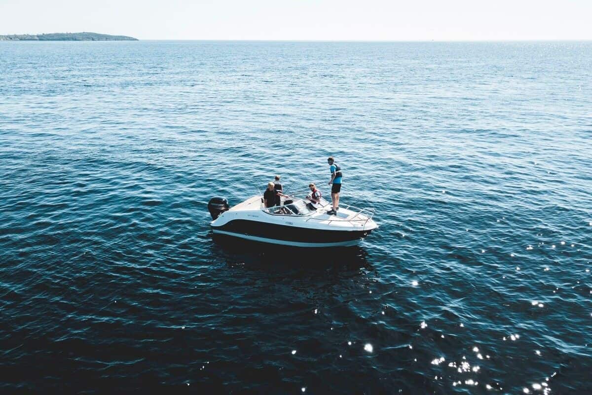 Two people engaging in water sports on a small motor boat, with slipping risks.
