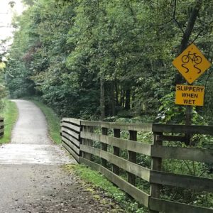 A wooden bridge in the woods with a sign on it promoting safety.