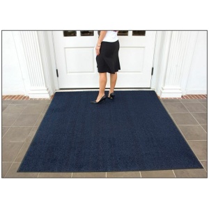 A woman standing in front of a door with a Brush Hog Floor Mat.
