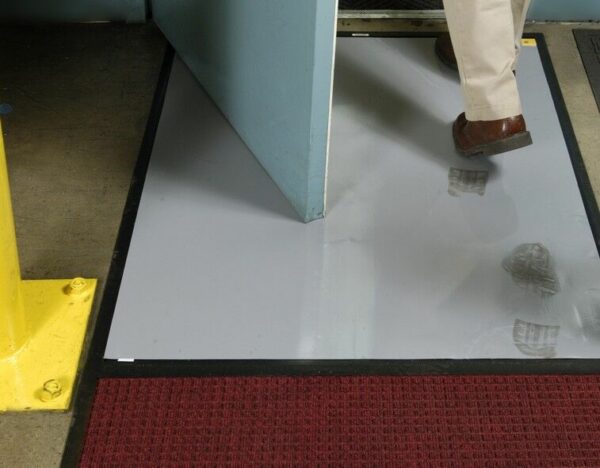 A man is walking into a doorway with a Clean Stride Dirt Removal Frame With Carpet mat.