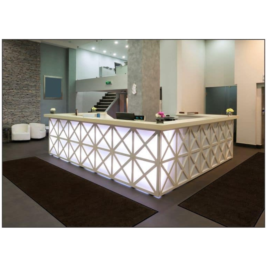 The reception area of a hotel with a white counter and Plush Floor Mat.