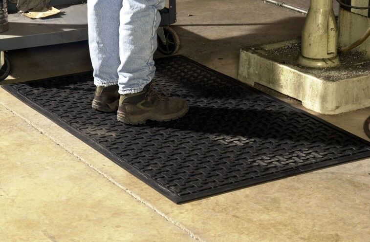 A person standing on a safety mat in a warehouse or factory.
