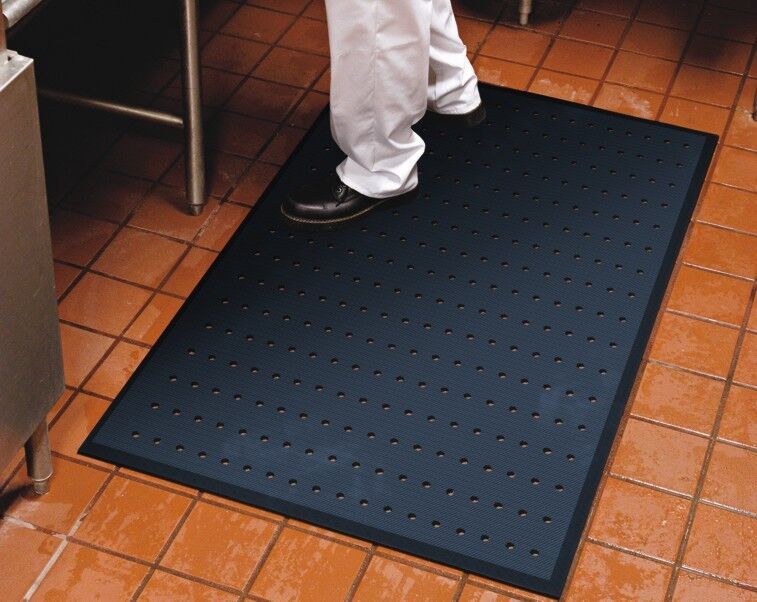 A person standing on a Complete Comfort Floor Mat in their kitchen.