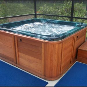 A deck with a hot tub and blue rug, ensuring pool safety.
