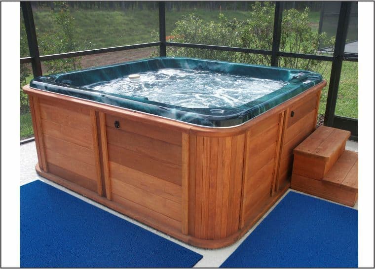 A deck with a hot tub and blue rug, ensuring pool safety.