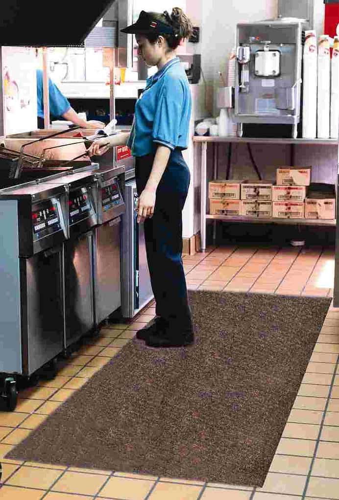 A woman is standing among kitchen mats.