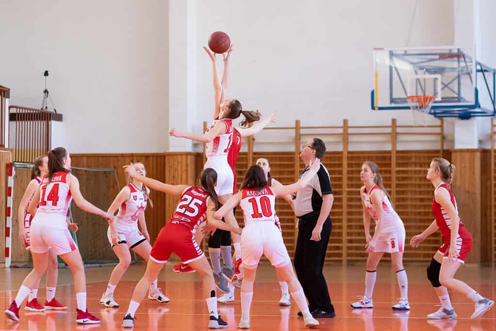 A group of girls playing basketball on floormats in a gym, prioritizing school safety.