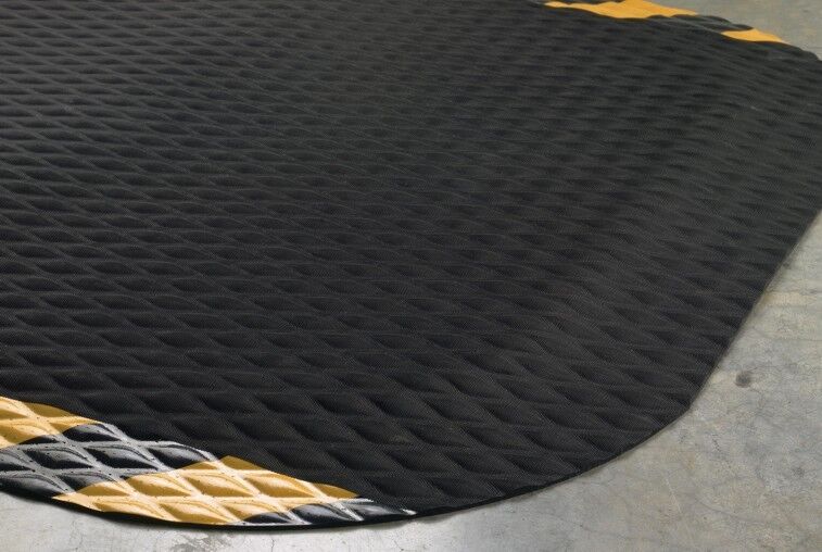 A black and yellow Hog Heaven Floor Mat on a concrete floor.