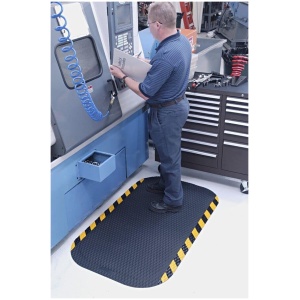 A man utilizing a machine in a factory while standing on Hog Heaven Floor Mat.