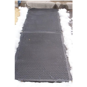 A black HOT-blocks™ Door / Landing Mat on a sidewalk with snow on it.