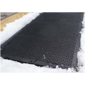 A black HOT-blocks™ Walkway / Driveway Mat is sitting on top of the snow, designed specifically for blocking hot surfaces like walkways and driveways.