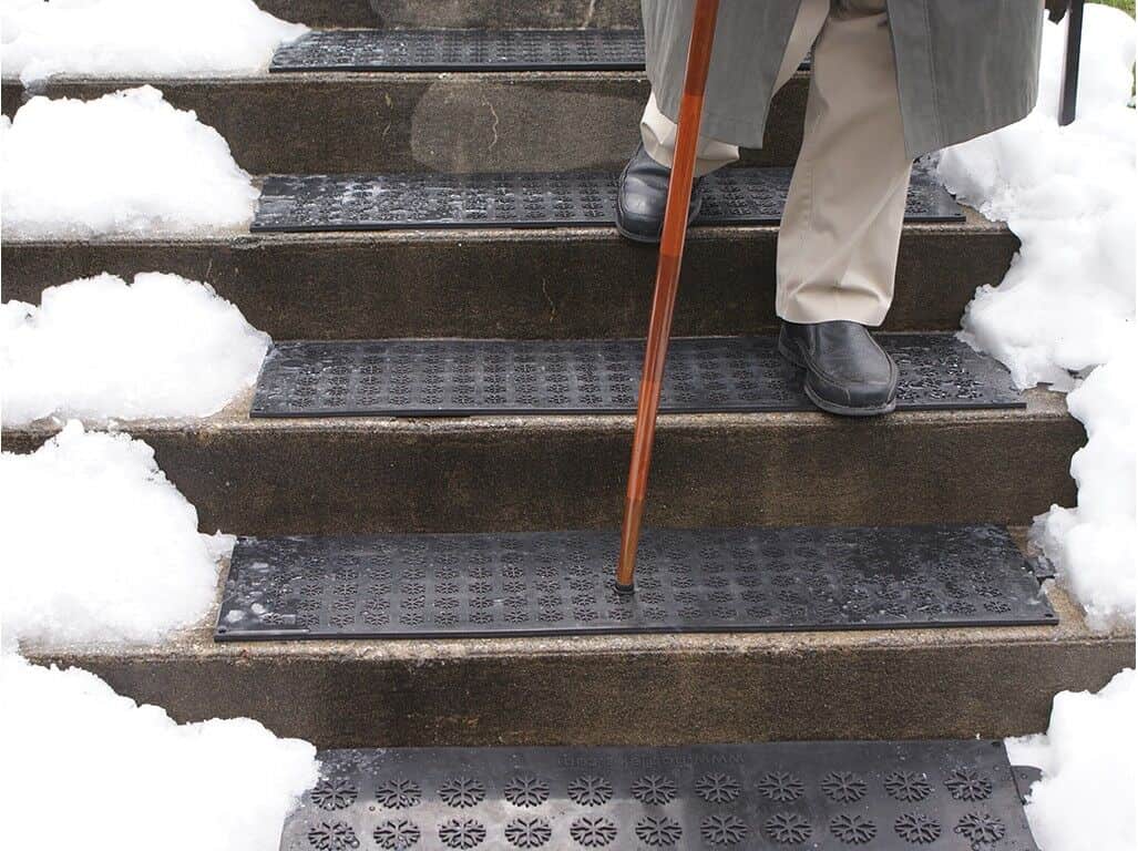 A man descending snowy stairs with a cane.