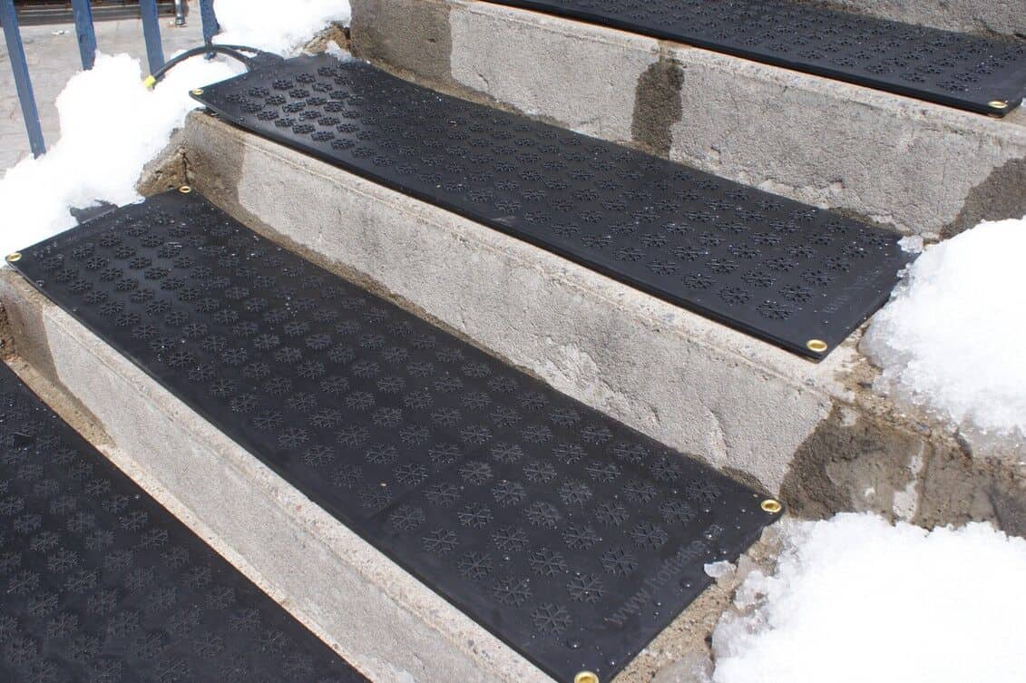 Black rubber steps with snow on them in types of heated floor mats.