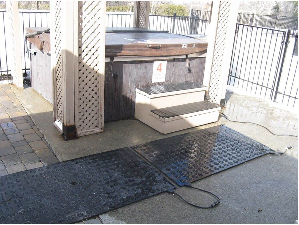 A hot tub on a concrete patio with HOTFlake Walkway / Driveway Mat.