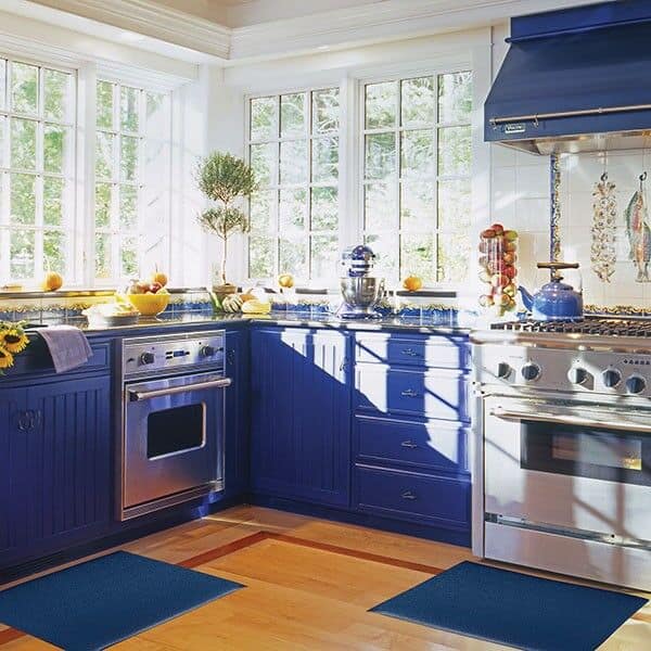 A kitchen with blue cabinets and blue floor mats.