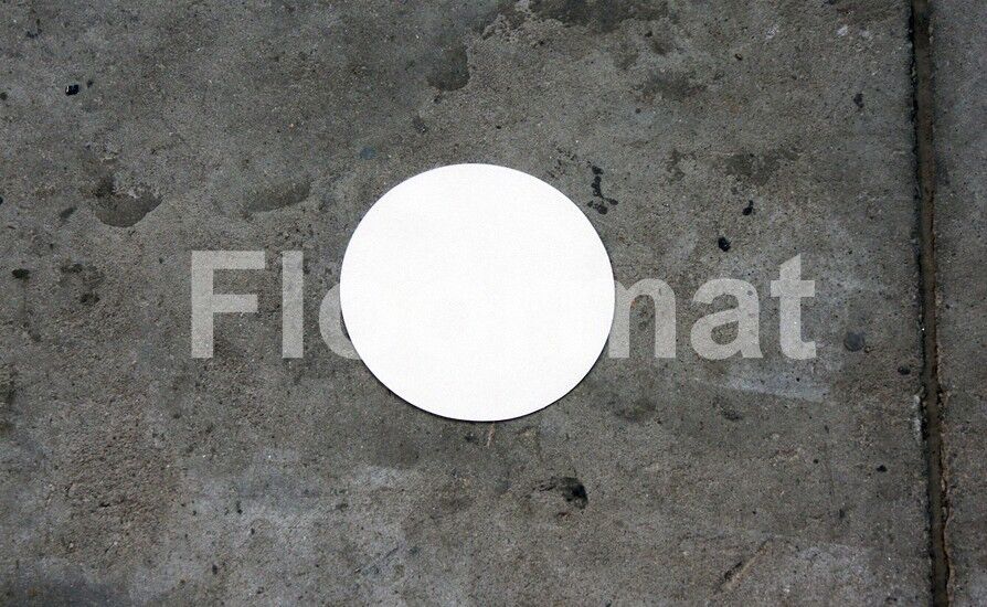 A white Disk Pallet Floor Markers on a concrete floor.