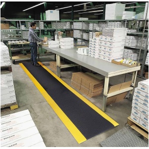 A man standing in a warehouse surrounded by the Razorback Dyna Shield Floor Mats and boxes.