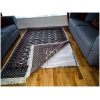 A RugBuddy Under Rug Heating Panel is placed under the rug on top of a wooden floor.