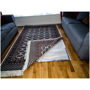 A RugBuddy Under Rug Heating Panel is placed under the rug on top of a wooden floor.