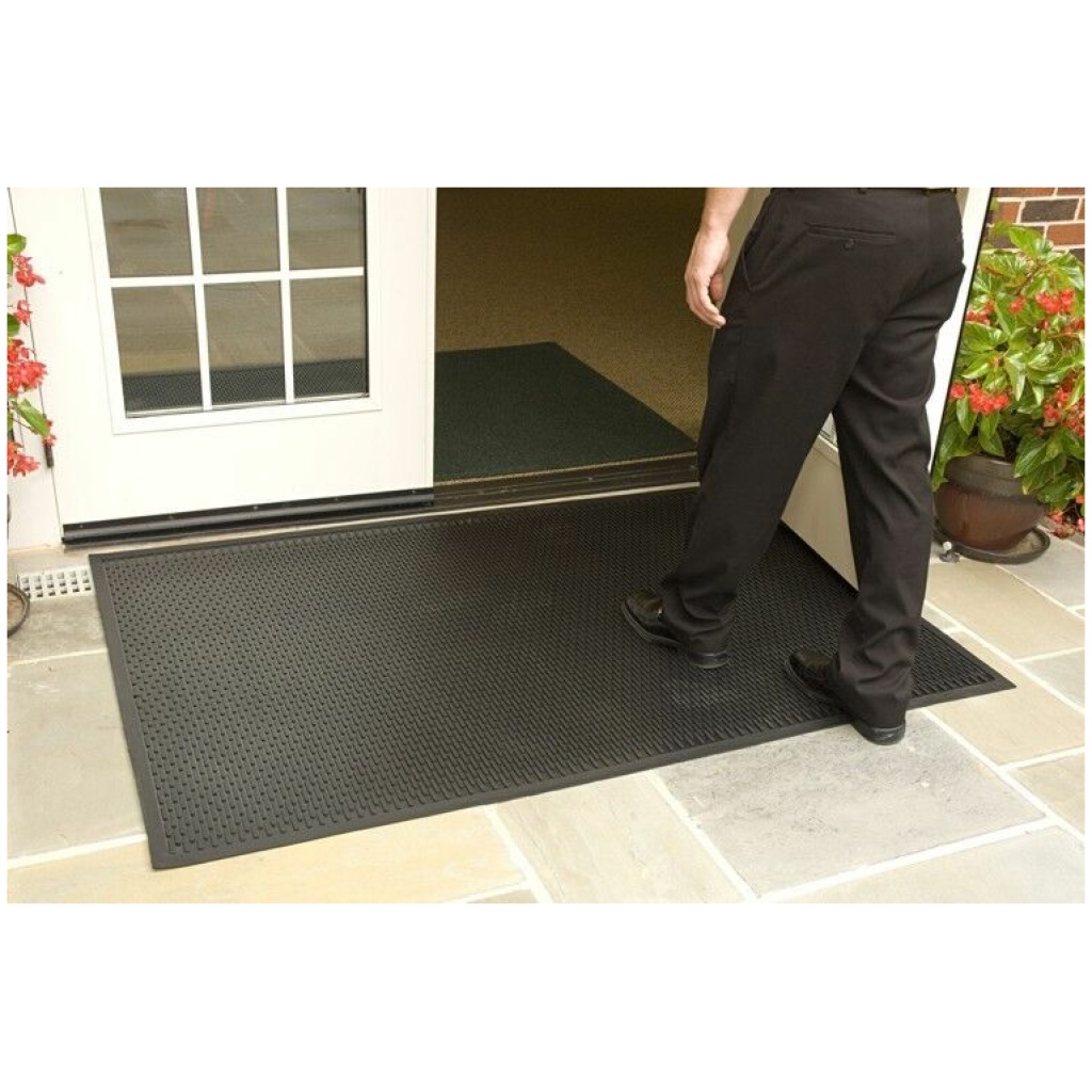 A man standing in front of a door with a Super Scrape Floor Mat Super Scrape Floor Mat.