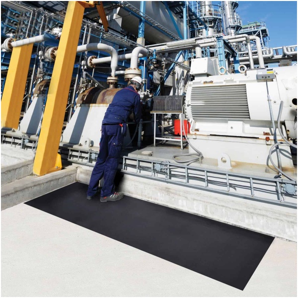 A worker is standing on SwitchBoard Matting in front of a machine.