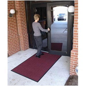 A woman entering a building on a WaterHog Classic Floor Mat.