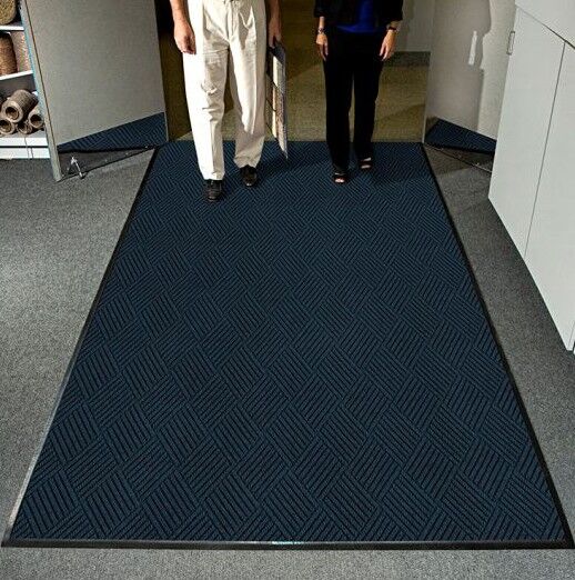 Two people standing in front of an office door with a WaterHog Eco Premier Floor Mat.