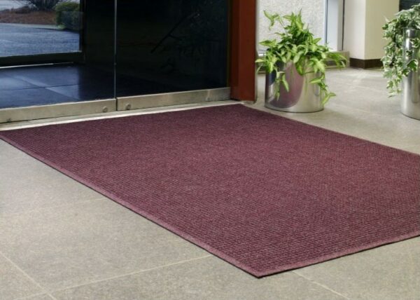 A WaterHog Squares Fashion Mat placed inside a building foyer.