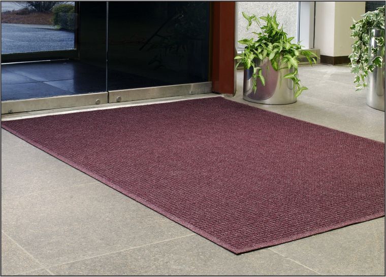 A burgundy door mat in front of a glass door.