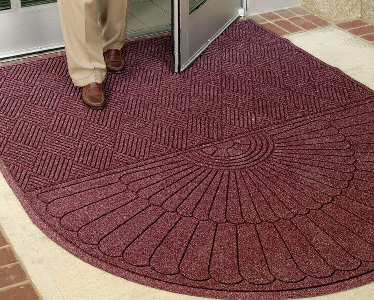 A person standing in front of a door with a WaterHog Eco Grand Mat.