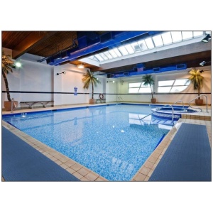 An indoor swimming pool with a Wet Step Floor Mat in a large building.